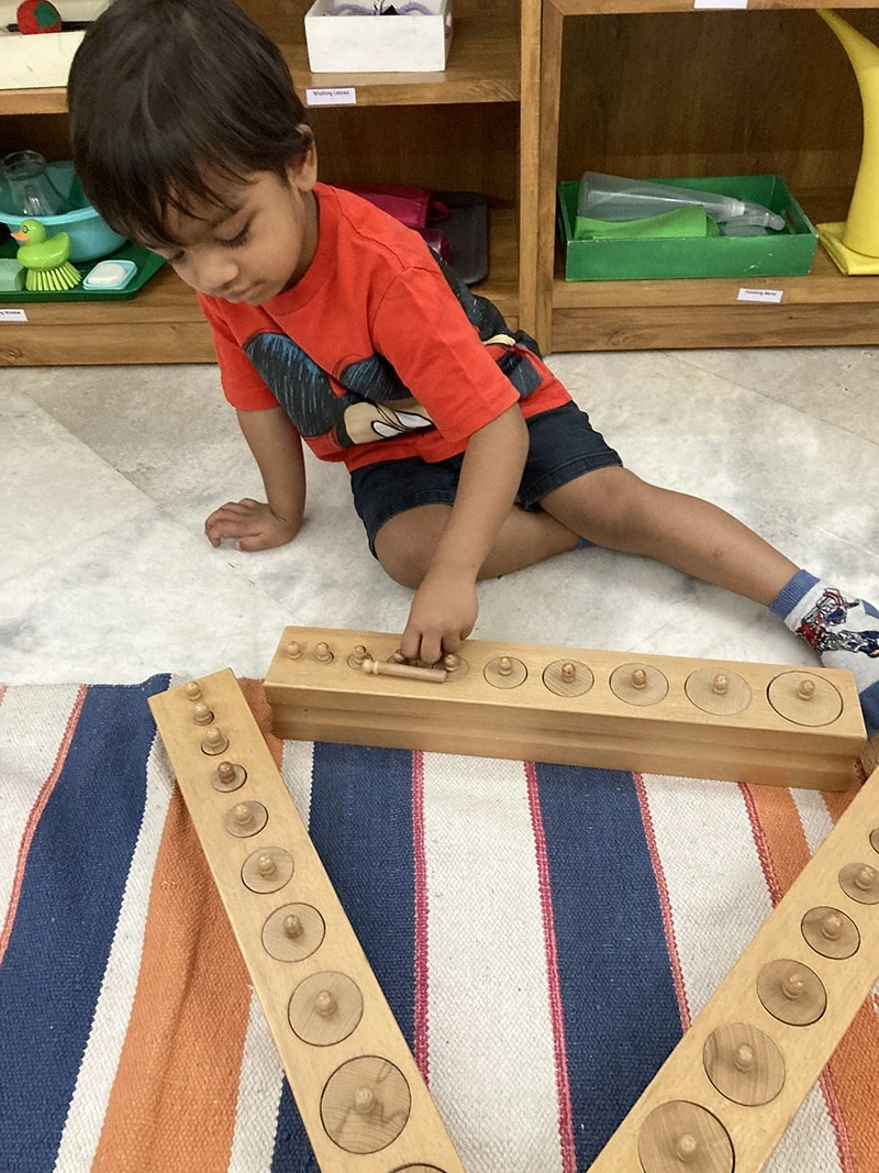 Boy operating a hand sewing thread loop frame independently