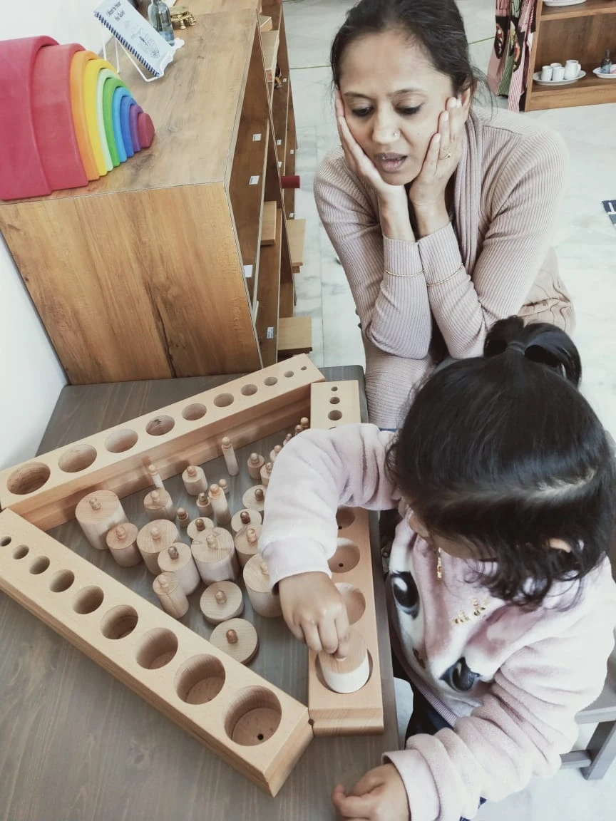Child building the Pink Tower apparatus with a guide